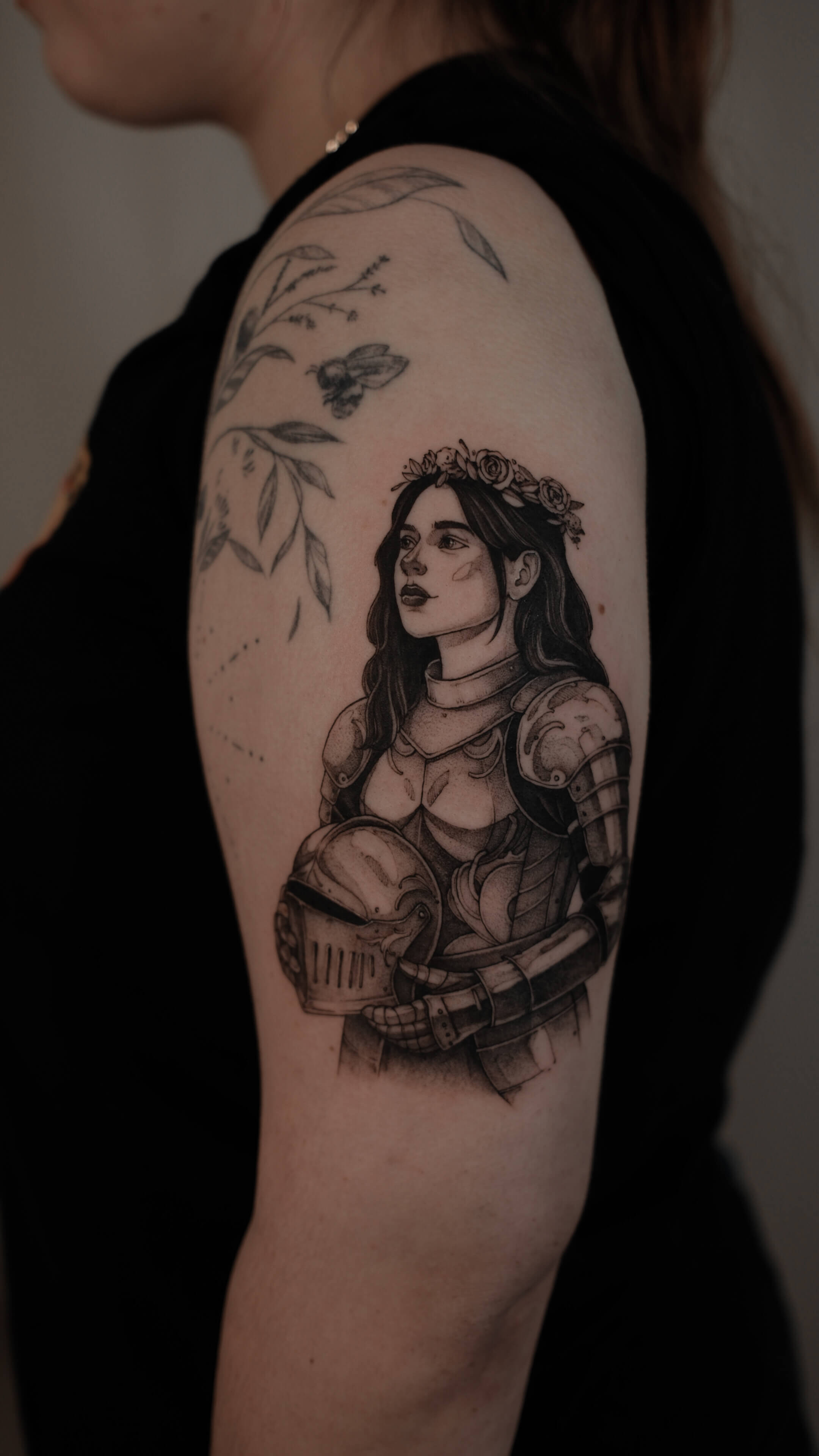Graphic tattoo of armoured woman warrior with flower crown on shoulder — tattoo Barcelona