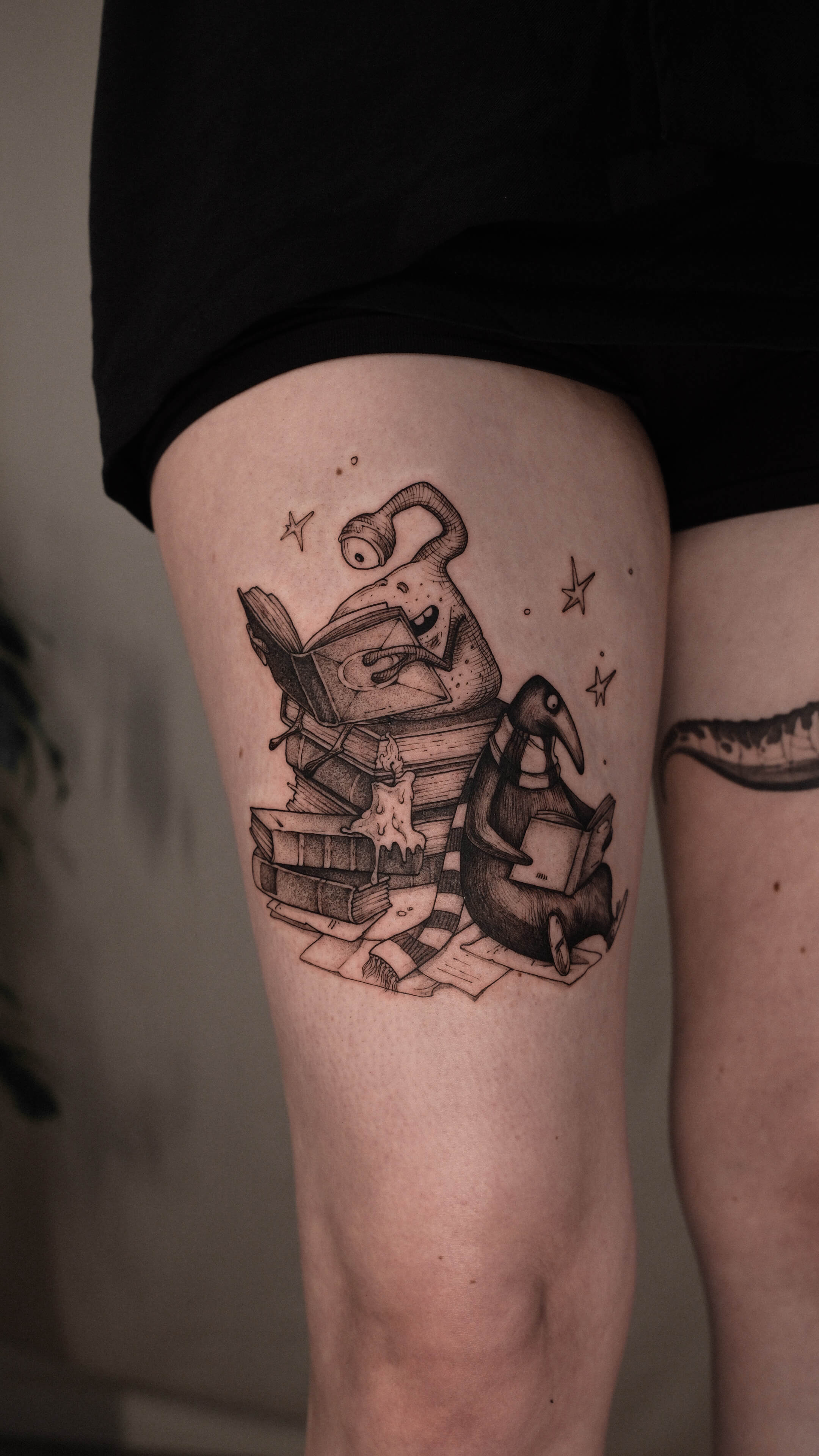 Sketch tattoo of a ghost and penguin reading books on thigh — tattoo Barcelona