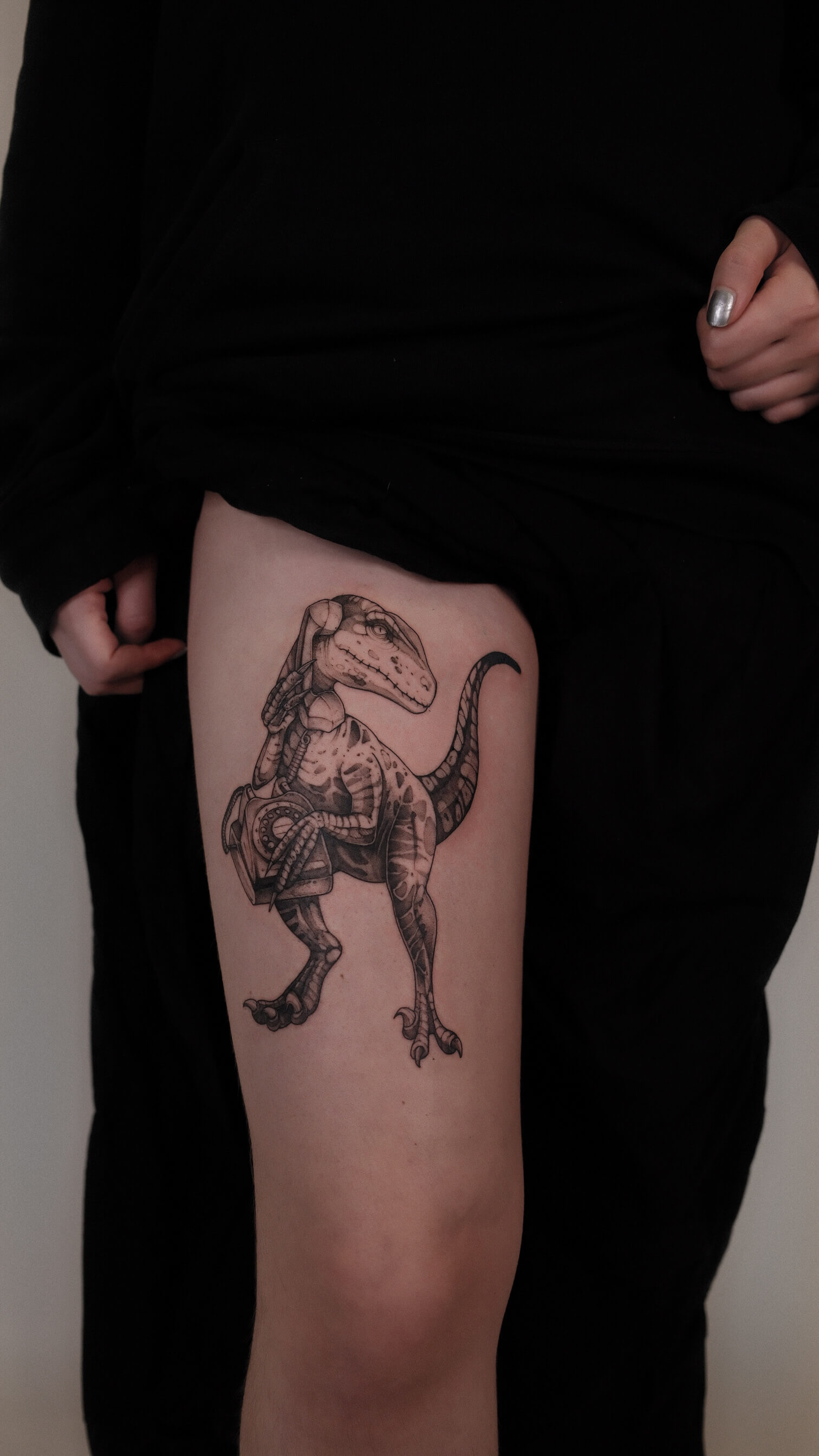Graphic tattoo of an armoured velociraptor on thigh — tattoo Barcelona